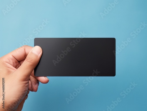 Male hand holding a black bank card on a blue background AI