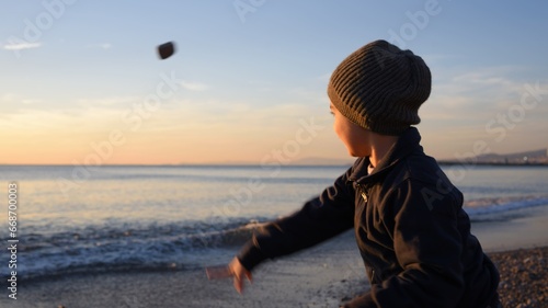 Bambino che lancia sassi (e le sue speranze) verso il cielo, verso l'orizzonte: verso il futuro! photo