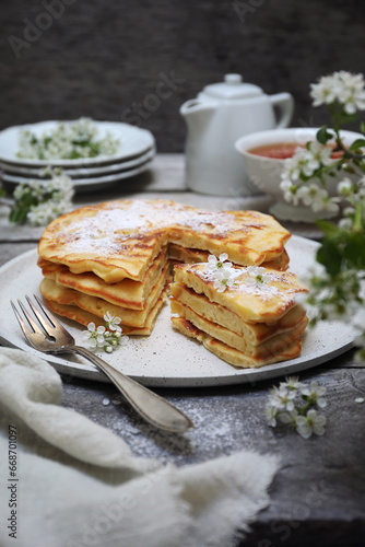 French cuisine. Matefaim. Stack of sweet Apple Pancakes, cup of tea and white spring flowers