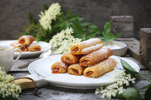 Fripons, French pastries. Apricot jam sweet puff pastry rolls and spring elderberry flowers