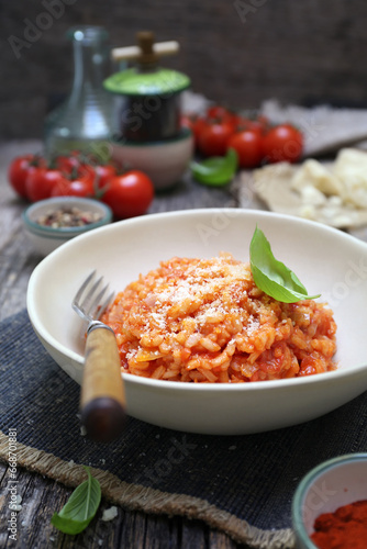 Italian cuisine. Plate of tomato risotto, olive oil, basil and cherry tomatoes