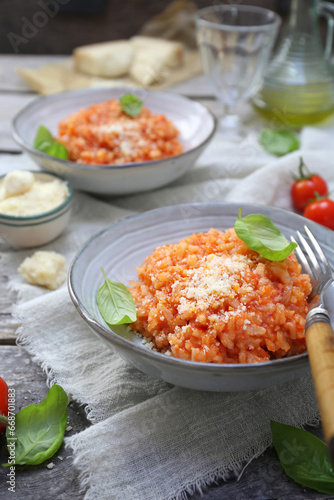 Italian cuisine. Plate of tomato risotto, olive oil, basil and cherry tomatoes, two servings