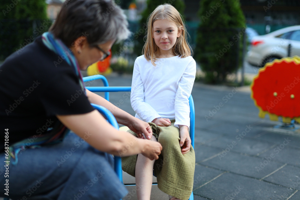 Young girl in tears, comforted by her mother after a painful playground ...