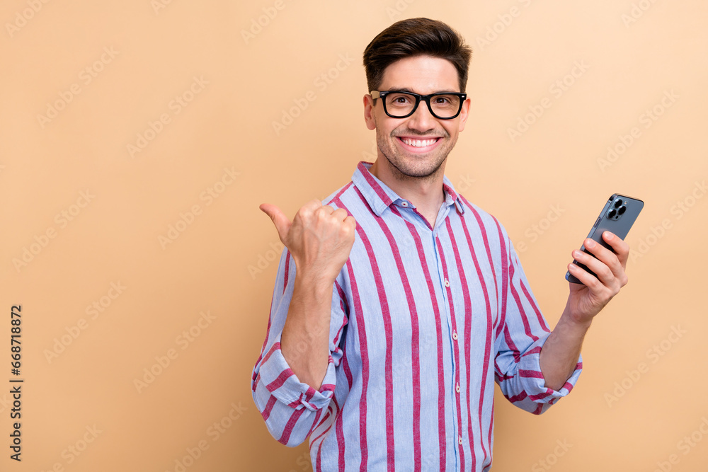 Portrait of successful ceo manager holding phone pointing finger empty space download google spreadsheet isolated on beige color background Portrait of successful ceo manager holding phone pointing finger empty space download google spreadsheet isolated on beige color background