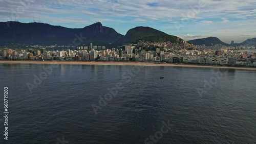 Drone Footage of Ipanema Beach in Rio De Janeiro in Brazil. The video is a trackline movement above the sea with subject being boats and the beach behind.