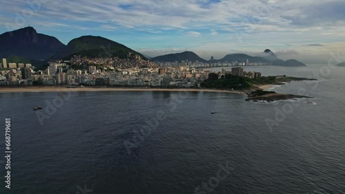 Drone Footage of Ipanema Beach in Rio De Janeiro in Brazil. The video is a slow dolly forward movement and going lower. In front we see the ipanema beach and a boat.