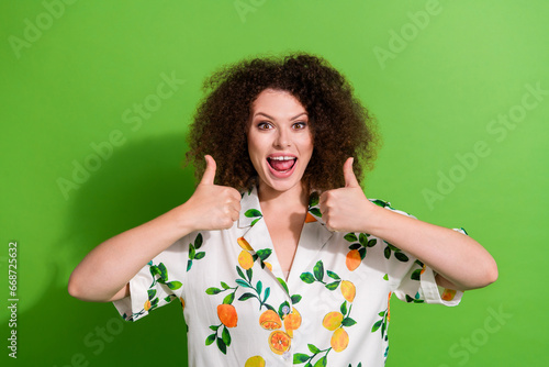 Photo of excited impressed girl dressed print shirt showing two thumbs up isolated green color background © deagreez