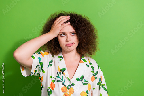 Portrait of disappointed lady hands touch head look empty space contemplate isolated on green color background