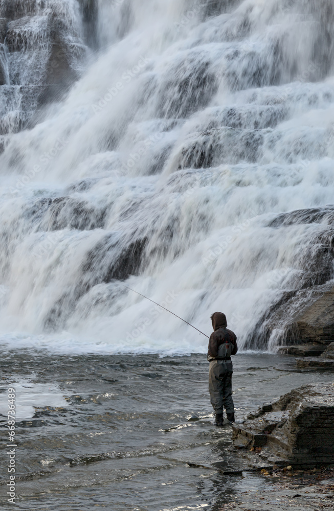 man with fishing rod in creek (shot from behind, no face, unrecognizable) in ithaca, new york