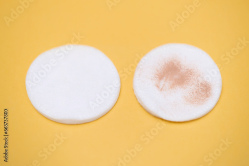 Girl holding a cotton pad in her hand, sponge for removing make-up, on yellow background. Foundation cream.