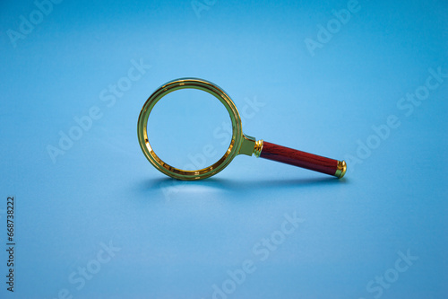 Magnifying glass with colored frame The handle is made of wood on a blue background.