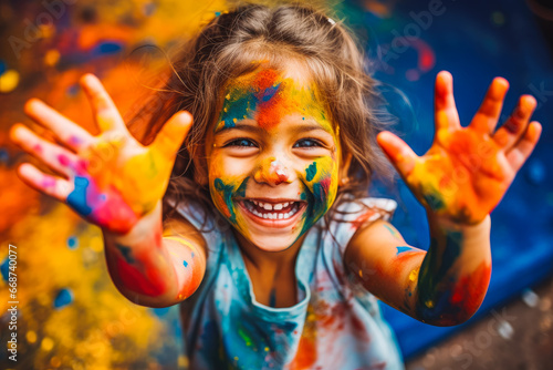 Little girl playing with colors. Child painting and paint on their face.