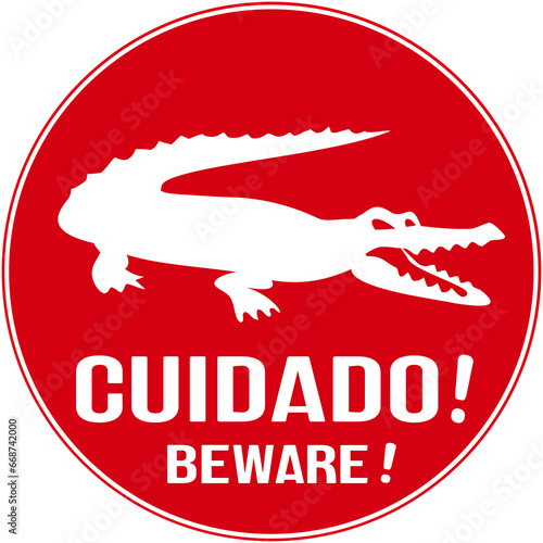 A red sign that warns: beware of crocodile or alligator in english and portuguese language. photo