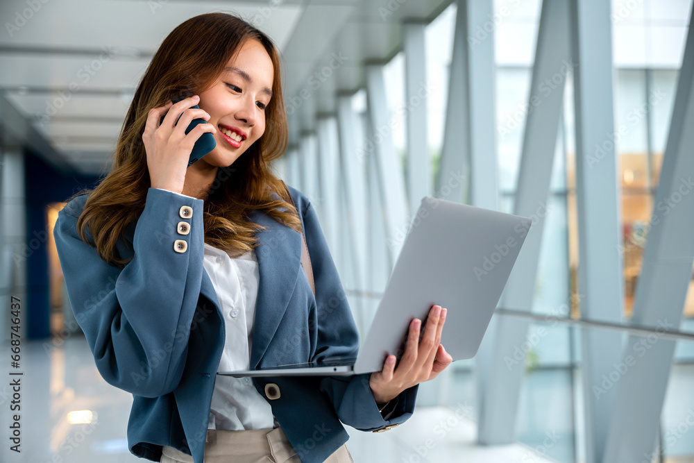 Professional woman using laptop and cellphone to multitask in airport, staying connected while traveling Professional woman using laptop and cellphone to multitask in airport, staying connected while traveling