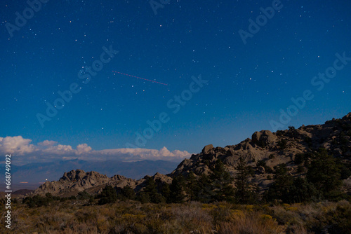 Star and lights from Bishop  California seen in long exposure picture taken in the Buttermilks at the foothills of the sierra nevada mountains.