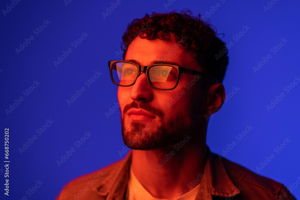 Obraz premium Portrait of young handsome man looking away against gradient purple background in neon light.