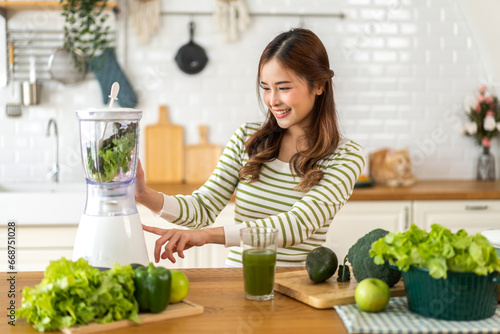 Portrait of beauty healthy asian woman making green vegetables detox cleanse and green fruit smoothie with blender.young girl drinking glass of smoothie, fiber, chlorophyll in kitchen.Diet, healthy © Art_Photo