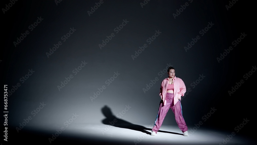 Attractive woman dancing jazz-funk in a studio. Black to white soft gradient background, white spotlight and distinct falling shadow. Modern choreography. Full length.