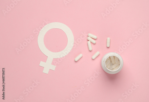 Female gender symbol with pills on pink background photo