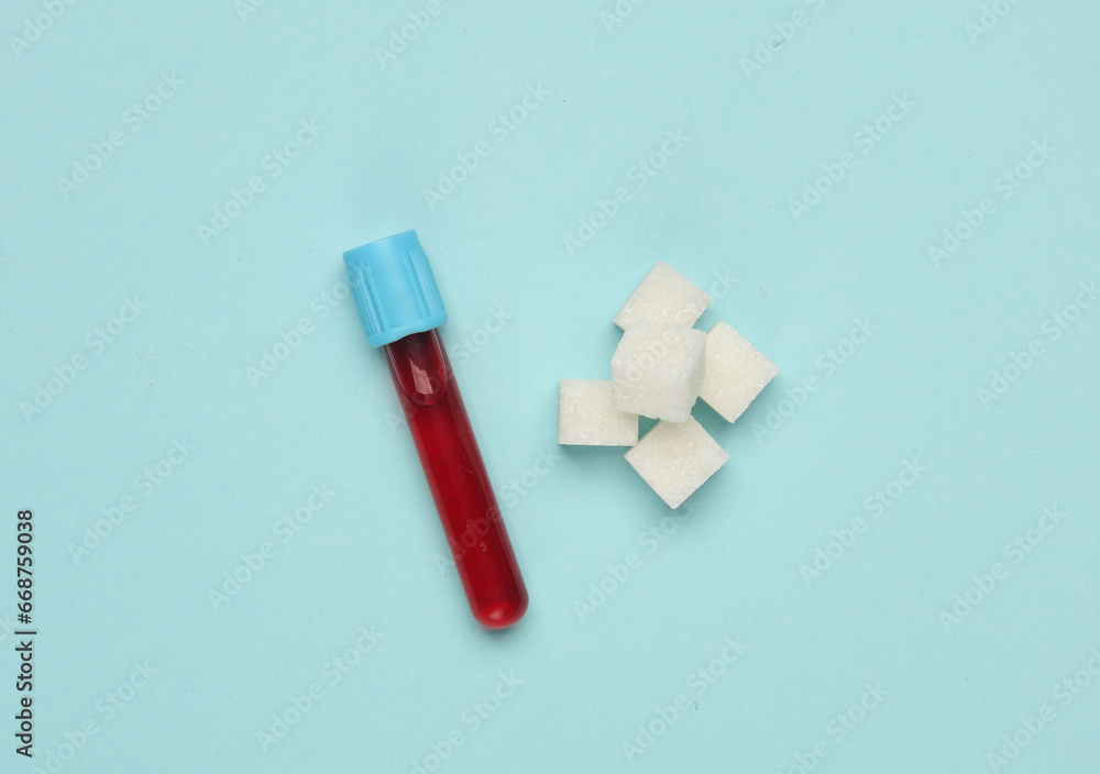 Blood test tube and sugar cubes on a blue background. Blood sugar concentration, diabetes Blood test tube and sugar cubes on a blue background. Blood sugar concentration, diabetes