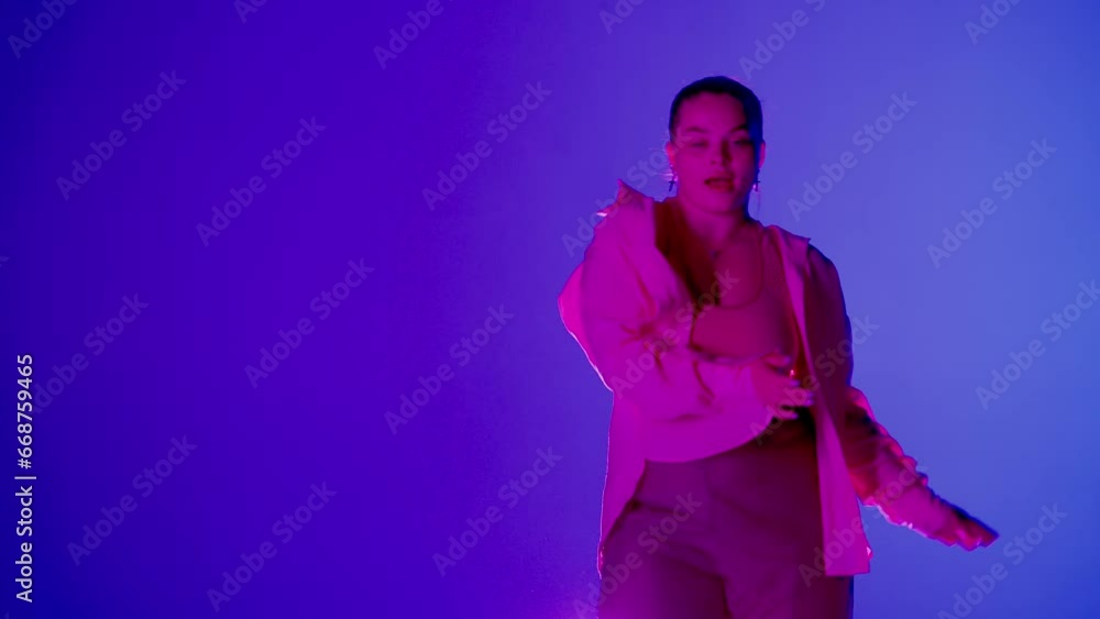 Attractive woman dancing jazz-funk in pink and blue neon light in a studio. Modern dynamic and energetic dance choreography. Medium full. Attractive woman dancing jazz-funk in pink and blue neon light in a studio. Modern dynamic and energetic dance choreography. Medium full.
