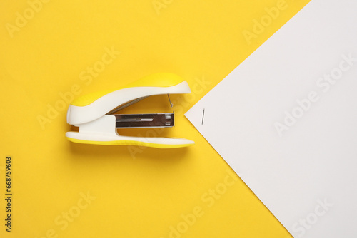 Stapler with sheets of paper on a yellow background photo