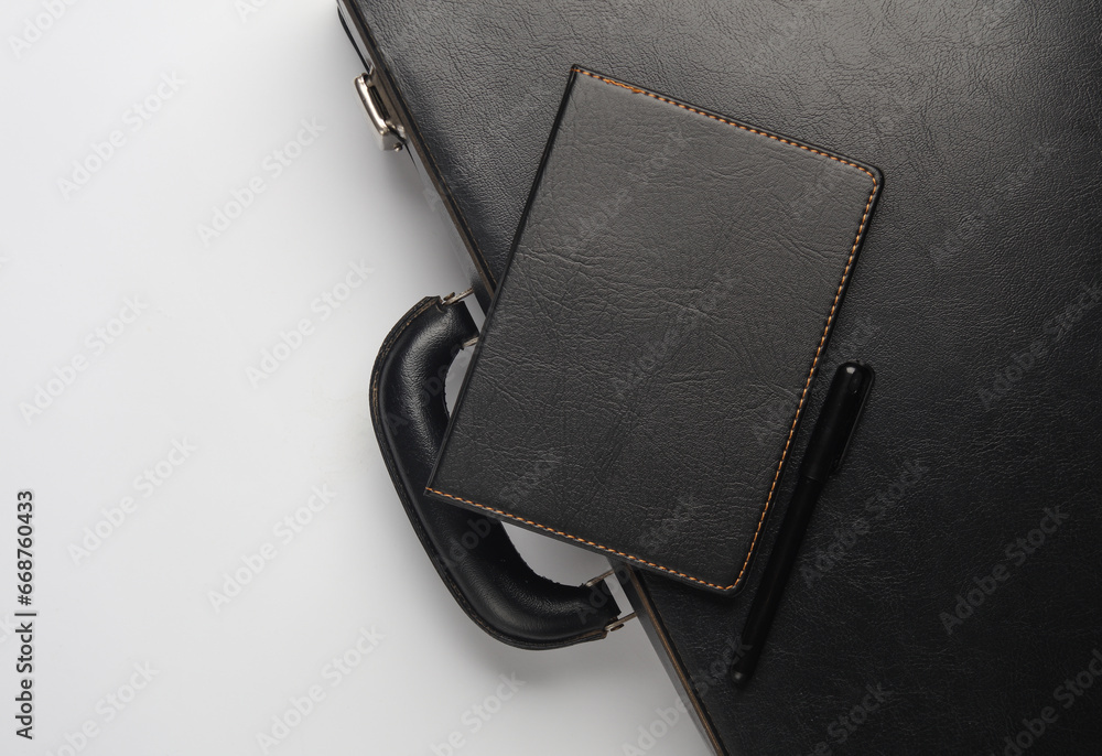 Leather suitcase with notebook on white background. Business concept. Top view Leather suitcase with notebook on white background. Business concept. Top view