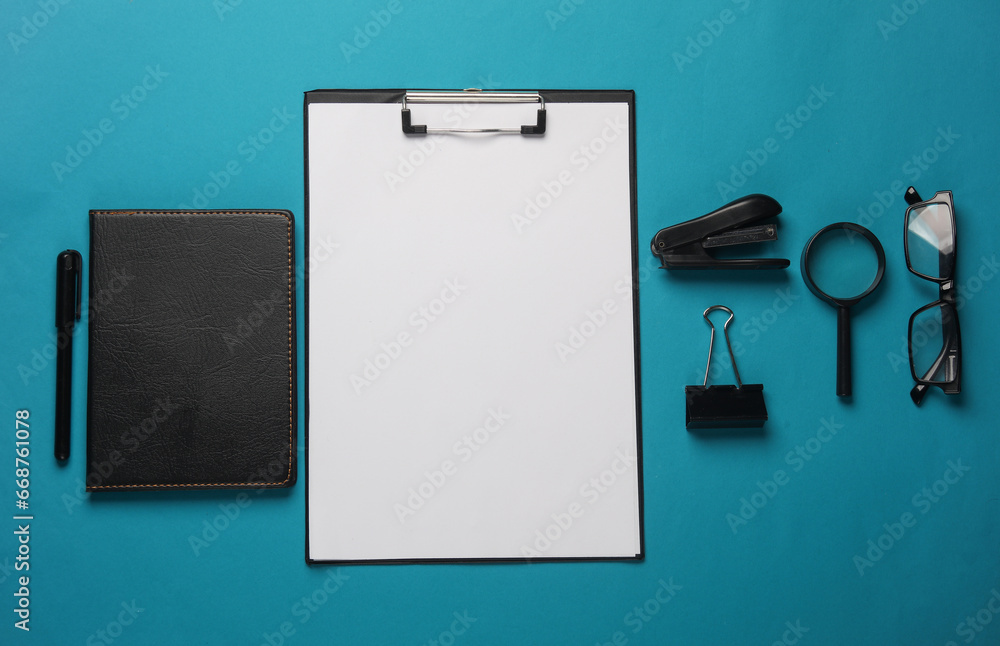 Clipboard and office stationery on blue background. Flat lay Clipboard and office stationery on blue background. Flat lay
