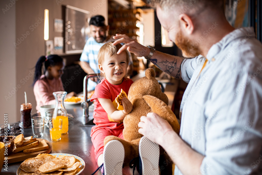 Loving gay fathers enjoying breakfast with their children at home Loving gay fathers enjoying breakfast with their children at home