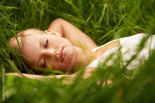 Nature face, grass field and relax woman sleep, tired or leisure for outdoor wellness, calm wellbeing or countryside peace. Girl dream, freedom and park break with green lawn, pitch or garden growth