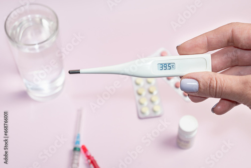 In a female hand is a white electronic thermometer a high temperature. Measured body temperature during illness