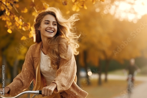 A happy active woman in stylish clothes rides a bicycle in the autumn park © Julia Jones