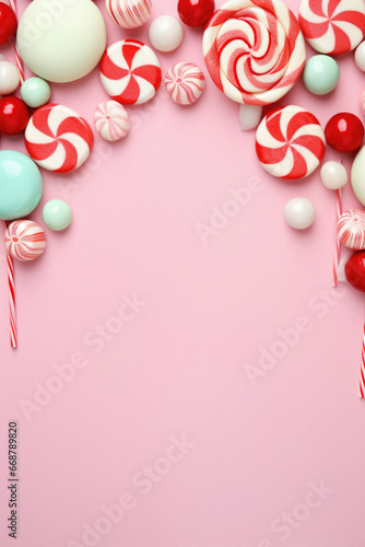 Christmas candy canes and christmas decorations on pink background.
