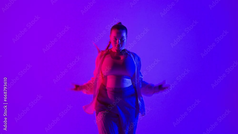 Attractive woman dancing jazz-funk on pink and blue neon background in a studio. Modern dynamic and energetic dance choreography. Medium full. Attractive woman dancing jazz-funk on pink and blue neon background in a studio. Modern dynamic and energetic dance choreography. Medium full.