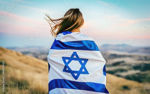 A woman wrapped in Israel flag standing with her back outdoor on nature background photo