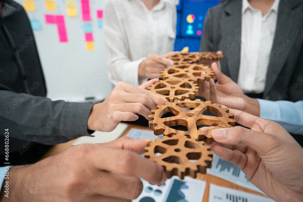 Office worker holding cog wheel as unity and teamwork in corporate