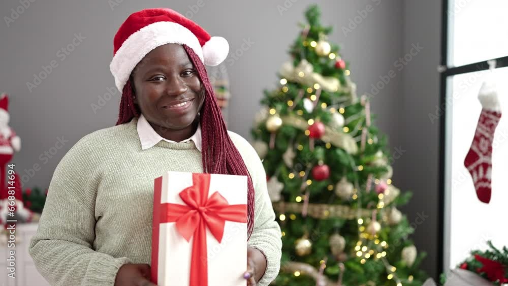 African woman with braided hair holding christmas gift at home African woman with braided hair holding christmas gift at home