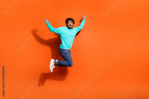 Full length photo of overjoyed funny jumping boyfriend celebrate his girlfriend approved him for date isolated on orange color background