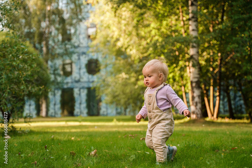 Cute blonde baby toddler in the park at sunset . The concept of a happy childhood