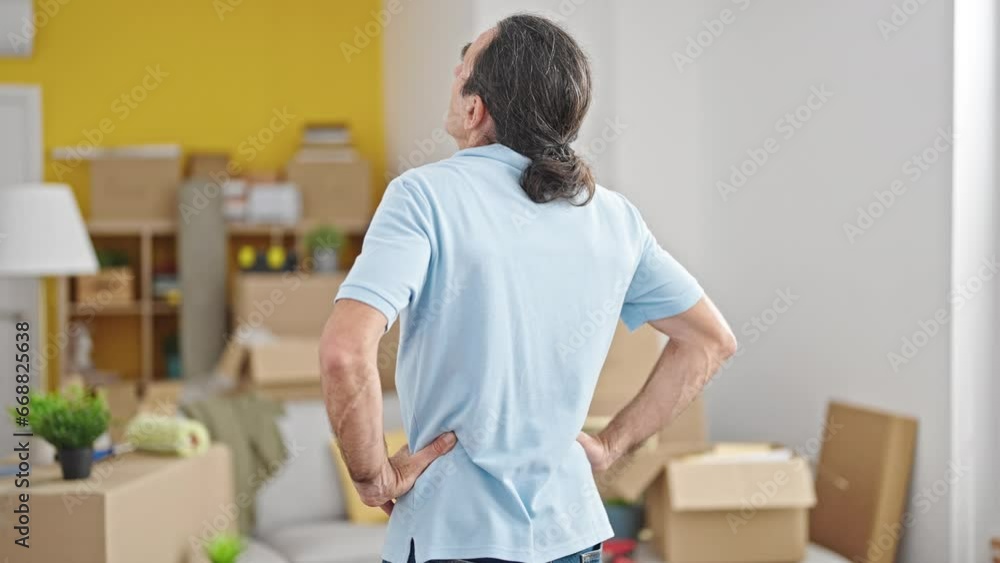 Middle age man standing backwards looking around at new home Middle age man standing backwards looking around at new home