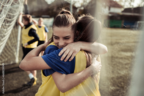 Two young female soccer players hugging during practice photo
