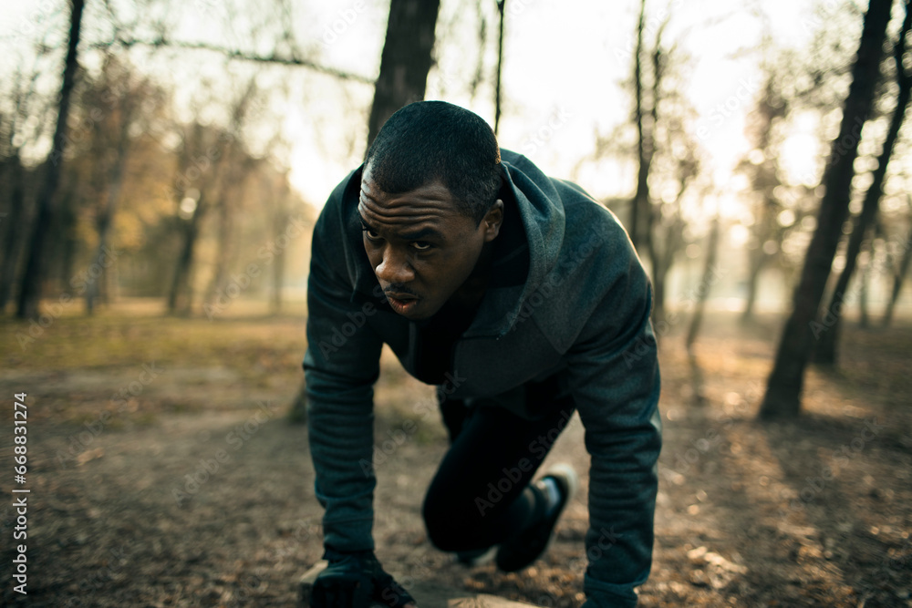Determined man in a crouched starting position ready to sprint in a park