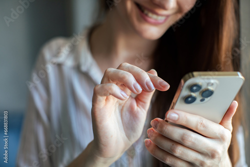 Close up of a young happy woman using her smartphone in the bedroom