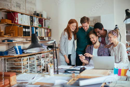 Group of diverse colleagues looking at a smartphone in a office