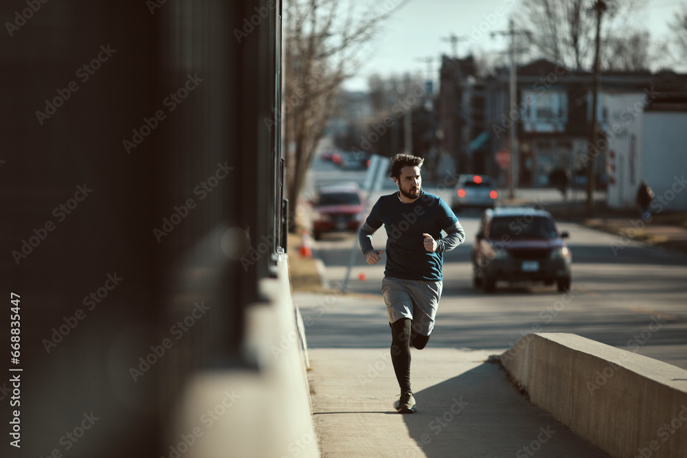 Young fit man running across the bridge