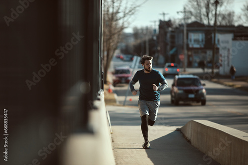 Young fit man running across the bridge