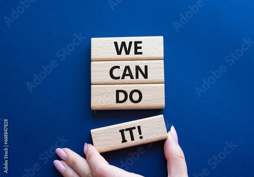 We can do it symbol. Concept words We can do it on wooden blocks. Beautiful deep blue background. Businessman hand. Business and We can do it concept. Copy space.