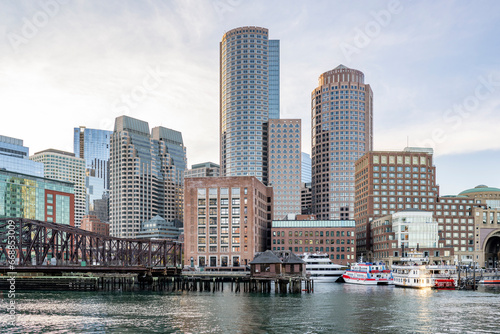 Rusty bridge to the embankment with moored ferries and other ships and boats in the center of the downtown of old Boston with skyscrapers