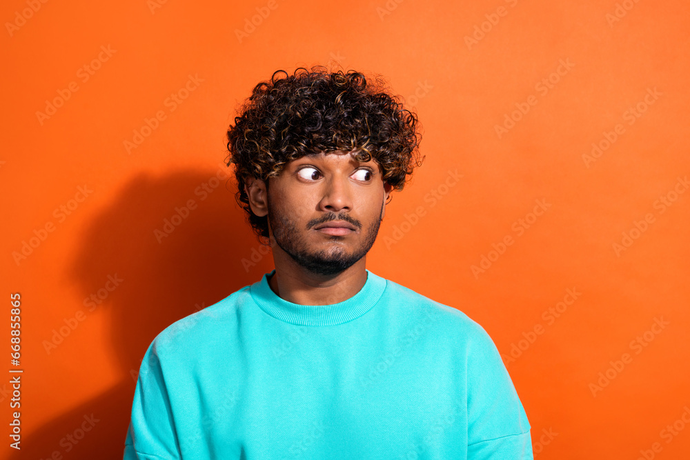 Photo of impressed minded person big eyes look empty space brainstorming isolated on orange color background Photo of impressed minded person big eyes look empty space brainstorming isolated on orange color background