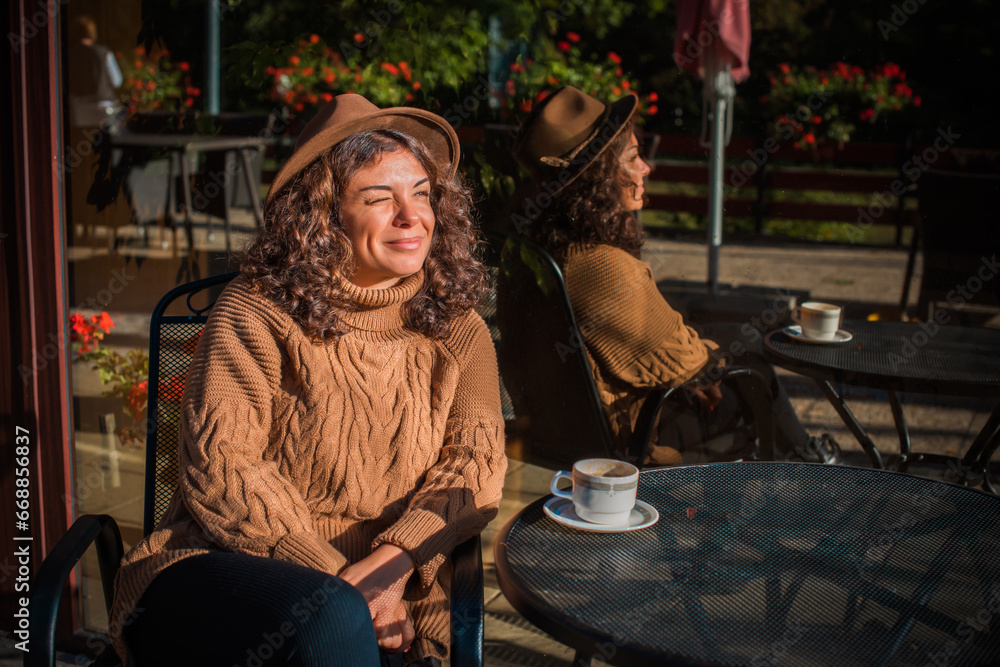 Modern Hispanic nice woman of middle age in knitted sweater with a cup of coffee at morning sunny day relaxing Modern Hispanic nice woman of middle age in knitted sweater with a cup of coffee at morning sunny day relaxing